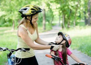 mom putting bicycle helmet on kid