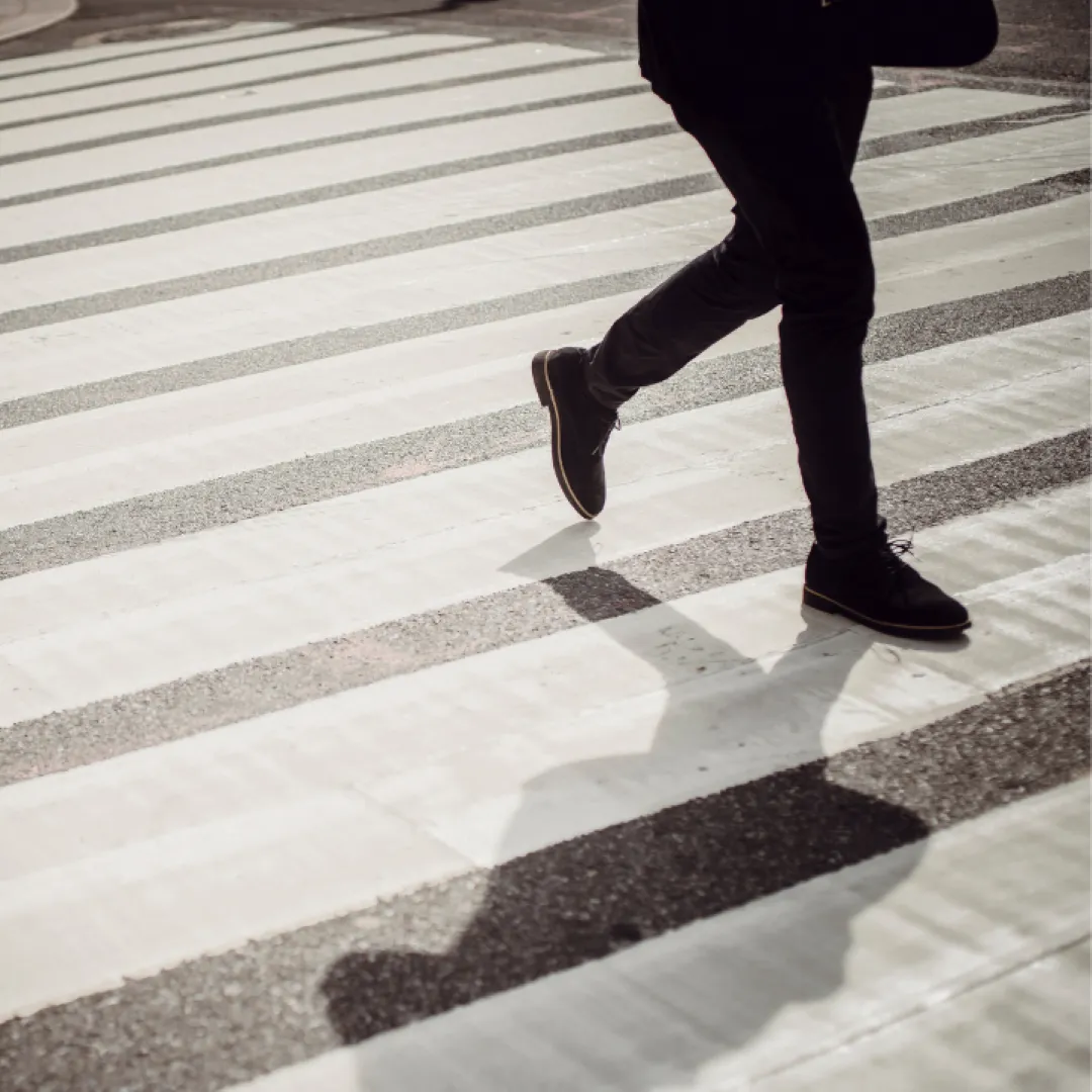 A person with black shoes and black pants walking across a white pedestrian crosswalk in columbus ohio - rinehardt pedestrian injury attorneys