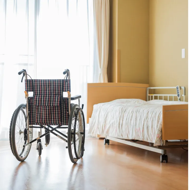 An Empty Wheelchair Next To A Bed With White Sheets - Nursing Home Neglect Attorneys In Mansfield