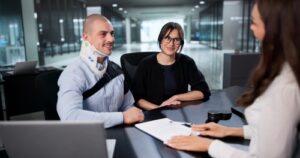 Injured worker wearing neck brace meeting with lawyer across desk
