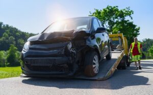 severely damaged car loaded onto flatbed tow truck after collision