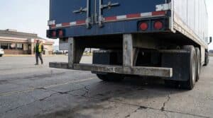 worker in safety vest walking near rear undercarriage of large commercial trailer